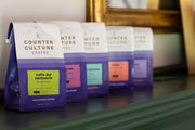 Photo of five single-origin coffees lined up on a fireplace mantel.